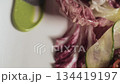 A man decorating plate with salad with vegetables and seafood. Spreading on a plate green sauce by metal spatula. Close-up high quality 4k footage 134419197