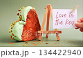 LOVE IS THE KEY text on paper note. Morning card Valentines day gift present Heart shaped pistachio croissant on green background with copy space. Puff pastry trendy sweet dessert bakery. Creamy dough 134422940