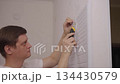 Man cutting soundproof panel with utility knife on interior wall for diy home improvement project, enhancing the room sound insulation and acoustics, close-up, side view. Shooting in slow motion. 134430579