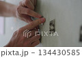 Hands peeling off residual double-sided tape from wall, representing home improvement, diy projects, wall preparation and cleaning tasks, closeup, unrecognizable person, slow motion. 134430585