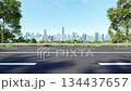 3D animation render of a wide asphalt road with white lane markings, flanked by trees and leading to a modern city skyline 134437657