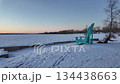 Scenic winter landscape features a vibrant turquoise chair on snow-covered shore, camera pans to reveal tranquil frozen lake and horizon 134438663