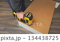 Individual using a power nail gun to secure wooden panels together, showcasing the assembly process in a well-lit indoor workspace 134438725