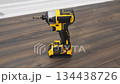 Power drill is positioned on wooden floor, showcasing its design and functionality, highlighting tool features and craftsmanship in action 134438726