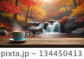 A loop video of a relaxing autumn scene with a waterfall flowing through a forest of autumn leaves and steaming coffee 134450413