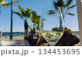 Wine glass on sunny beach with palm trees and ocean view during vacation 134453695
