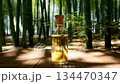Close-up of a rotating glass bottle with golden oil and a cork stopper in a serene bamboo forest 134470347
