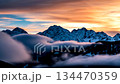 Majestic time-lapse of clouds flowing over snow-capped mountain peaks during a beautiful golden hour sunset 134470359