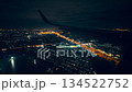 airplane flying over light of big city at night, take off or landing, view from window on wing 134522752