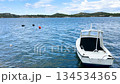 White fishing boat anchored in crystal clear turquoise Mediterranean waters with scenic coastal hills backdrop 134534365