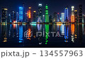 Vibrant city skyline at night with colorful skyscrapers reflecting on water 134557963