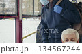 Front view of boy in mask and gloves sitting on bus. Passengers on bus, boy with earphones and rucksack, using smartphone, texting, putting in pocket. Concept of public transport. 134567244