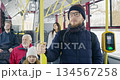 Front view of bus stopping at station, passengers waiting. Boy wearing sunglasses standing, pipe holding, girl, woman, old man, boy with earphones sitting. Concept of urban life. 134567258