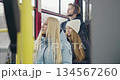 Side view of passengers going home by bus. Blonde woman sitting, young girl in white hat looking in window, boy with earphones listening to music. Concept of public transport. 134567260