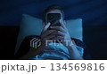 Man holds his smartphone close to face while brousing social media at night 134569816
