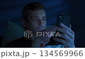 Tired man holding phone, doom scroling at night, feel frustrated and overwhelmed 134569966