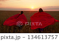 Superhero children running through wheat field. Girls playing in countryside. Healthy outdoor games for children. Child superhero run in winning costume through wheat field. Little girl in red cape 134613757