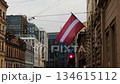 Cityscape with flag and tram wires, Latvian banner displayed amidst city skyline background Cityscape with flag and tram wires, Latvian banner displayed amidst city skyline background 134615112