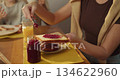 Caucasian mother prepping toast with berry jam for breakfast 134622960