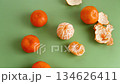 Fresh mandarins and peeled citrus segments on green backdrop 134626411