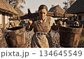 Medieval Peasant Woman Carrying Water in a Rustic Village 134645549