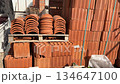 Stack of red clay bricks and roof tiles on wooden pallets in construction yard video 134647100