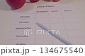 The concept of healthy nutrition in modern life. A diet plan printed on a piece of paper and a apples lying on a table 134675540