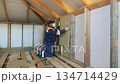 Insulation of a frame house with mineral wool. Cutting, fitting, laying insulation. Construction works. 134714429