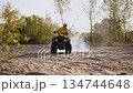 Female cyclist dashing across arid landscape on off road vehicle 134744648