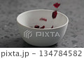 Slow motion dried cranberry falling into white bowl on terrazzo countertop 134784582