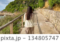 A brunette girl walks along the seashore. Follow me. Happy lady enjoys summer vacation on exotic island. 134805747