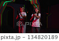 Portrait of teenage girls in laser tag with laser weapons in their hands, against the background of dark walls with neon stripes. The girls aim their guns. A modern laser tag arena. 134820189