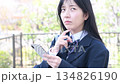 屋外でスマホを持ち悩むアジア人の女性学生 134826190