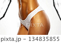 Close-up video of a fit female torso featuring golden tanned skin with a shiny, oiled texture. 134835855