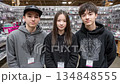 Three young people smiling and posing for a photo together at a commercial exhibition 134848555