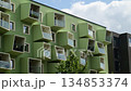 Green building facade with distinctive modern geometric balconies and windows under a blue sky 134853374