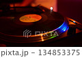 Turntable spinning a vinyl record, showcasing a vibrant club atmosphere with blue and orange lights 134853375