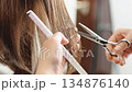 A novice hairdresser practicing cutting a woman's hair; close-up of hands 134876140