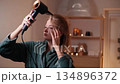 Woman drying her hair with a hairdryer. 134896372