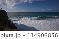 Person Standing on a Dramatic Cliff Overlooking Powerful Ocean Waves and Foaming Sea 134906856