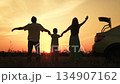 Happy family car trip, child parents picnic outdoors holiday, mother father kid raise hands up, people having fun, child day summer, warm nostalgic mood, sunset backlit silhouettes, peaceful rural 134907162
