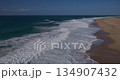 Powerful Atlantic Ocean Waves Crashing on a Wide, Sandy Beach Under a Clear Blue Sky 134907432