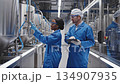 Professionals in blue lab coats collaborate in a modern facility, inspecting equipment and discussing processes, camera pans to capture teamwork 134907935