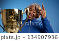 Celebratory moment of a joyful woman in blue jacket, proudly holding a trophy, camera zooms in on her smiling face and gestures of triumph 134907936