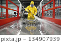 Worker in protective gear sprays surface with cleaning solution, showcasing industrial cleaning process, camera follows action with smooth movement 134907939
