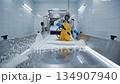Worker in protective gear cleans stainless steel surface with foam, showcasing effective sanitation process, camera pans across scene 134907940