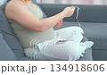 Pregnant woman sitting on a couch using her smartphone in a relaxed home setting. A calm everyday moment highlighting modern maternity lifestyle, comfort, and digital communication during pregnancy 134918606