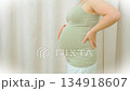 Asian Close up of pregnant woman gently holding her belly, wearing white top and light blue pants, symbolizing care and anticipation during pregnancy and motherhood. Vertical Video. High quality 4k 134918607