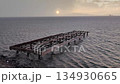 The sun peeking through the clouds after a rainy day, and the abandoned, broken pier. 134930665