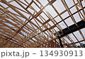 Workers are constructing wooden roofing frame of building with joins metal supports structure. 134930913